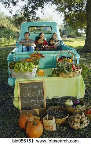 Stock Image - Multi-ethnic family in truck at farm stand. Fotosearch