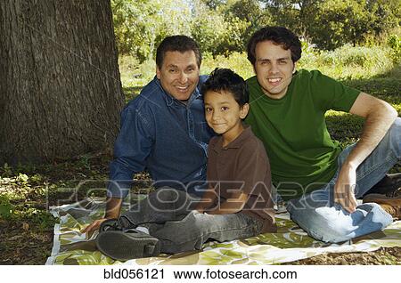 Stock Image - Multi-ethnic family sitting under tree. Fotosearch