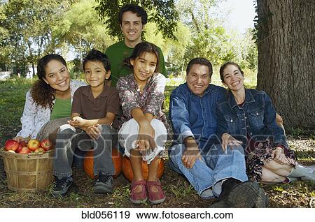 Stock Photo - Multi-ethnic family sitting under tree. Fotosearch