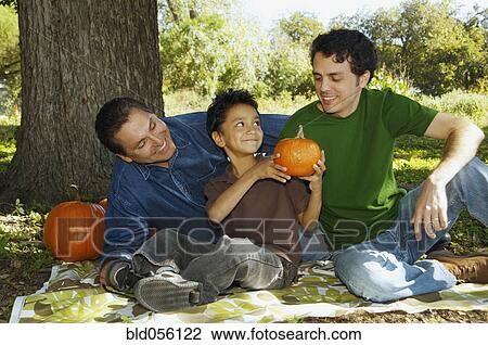 Stock Image - Multi-ethnic family with pumpkins under tree. Fotosearch