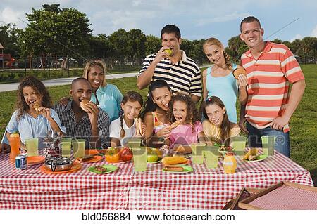 Multi-ethnic friends eating at picnic table View Large Photo Image Picture - Multi-ethnic friends eating at picnic table. Fotosearch