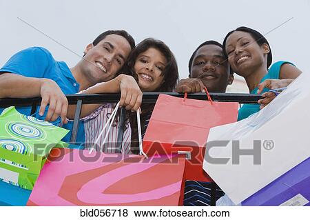 Multi-ethnic friends holding shopping bags View Large Photo Image Stock Photo - Multi-ethnic friends holding shopping bags. Fotosearch