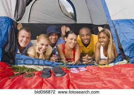 Stock Image - Multi-ethnic friends laying in tent. Fotosearch