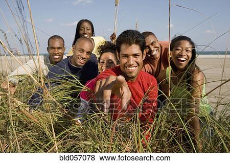 Stock Photo - Multi-ethnic friends looking through grass. Fotosearch