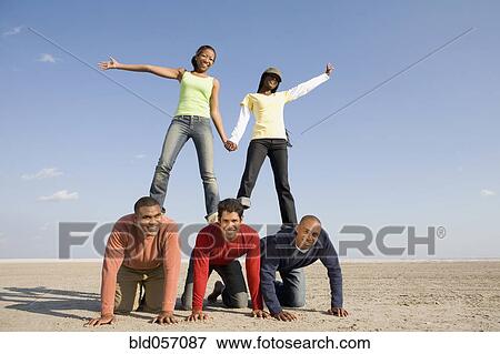 Stock Photo - Multi-ethnic friends making human pyramid. Fotosearch