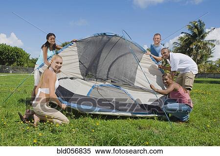 Stock Photography - Multi-ethnic friends setting up tent. Fotosearch