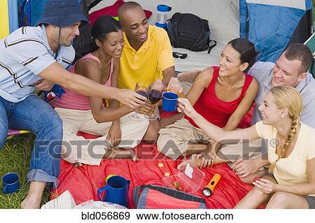 Stock Photo - Multi-ethnic friends toasting at campsite. Fotosearch