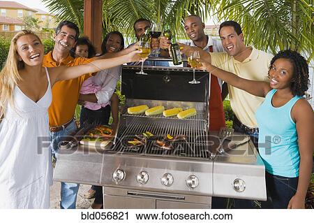 Stock Image - Multi-ethnic friends toasting over barbecue grill. Fotosearch