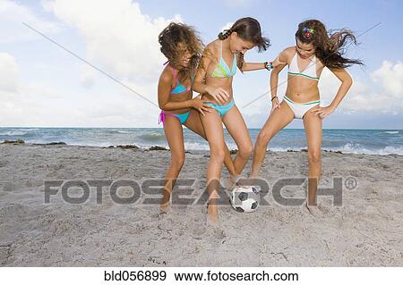 Stock Photo - Multi-ethnic girls playing soccer at beach. Fotosearch