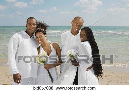 Stock Photo - Multi-ethnic newlyweds hugging at beach. Fotosearch