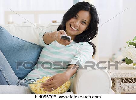Stock Photograph - Pacific Islander woman pointing remote control. Fotosearch