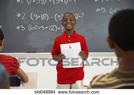 African American boy holding paper in front of class View Large Photo Image Picture - African American boy holding paper in front of class. Fotosearch