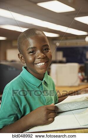 Stock Image - African American boy using library dictionary. Fotosearch