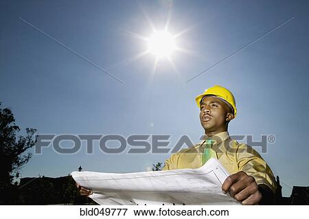 Stock Photo - African American businessman holding blueprints. Fotosearch