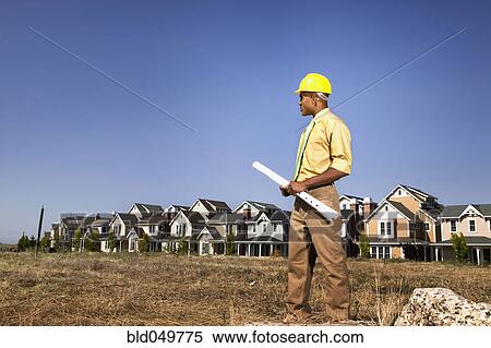Stock Photography - African American businessman holding blueprints. Fotosearch