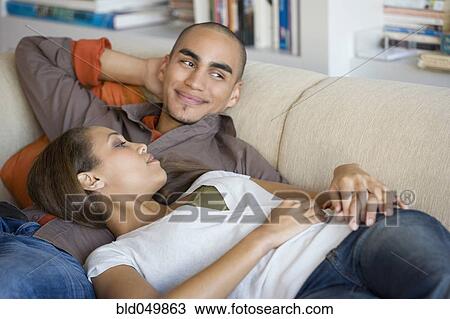 Stock Image - African American couple laying on sofa. Fotosearch