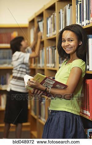 Stock Image - African American girl holding library book. Fotosearch
