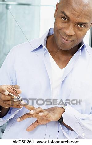 Stock Image - African American man clipping fingernails. Fotosearch