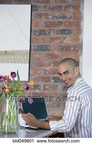 Stock Image - African American man dialing cell phone. Fotosearch