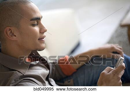 Stock Photography - African American man dialing cell phone. Fotosearch