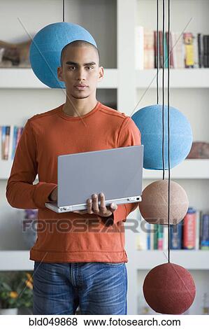 Stock Photo - African American man holding laptop. Fotosearch