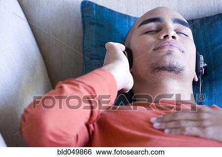 Stock Photograph - African American man listening to headphones. Fotosearch