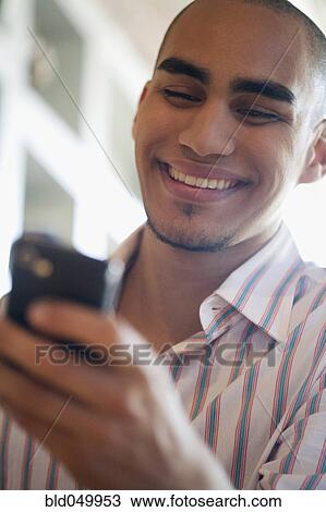 Stock Image - African American man looking at cell phone. Fotosearch