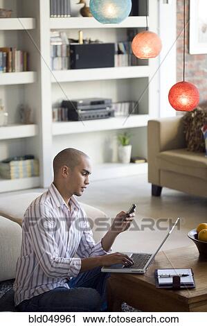 Stock Image - African American man looking at cell phone. Fotosearch