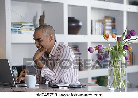 Stock Photo - African American man looking at laptop. Fotosearch