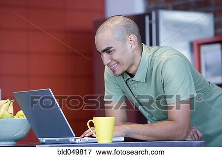 Stock Photo - African American man looking at laptop. Fotosearch