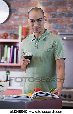Stock Image - African American man reading cookbook. Fotosearch