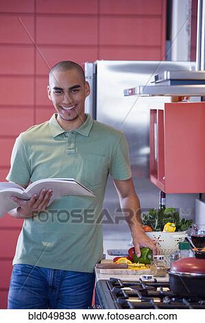 Stock Photo - African American man reading cookbook. Fotosearch