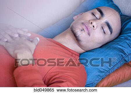 Stock Photography - African American man sleeping on sofa. Fotosearch