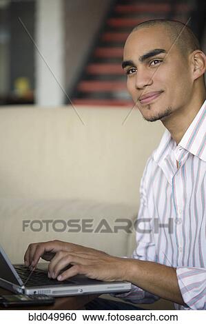 Stock Image - African American man typing on laptop. Fotosearch