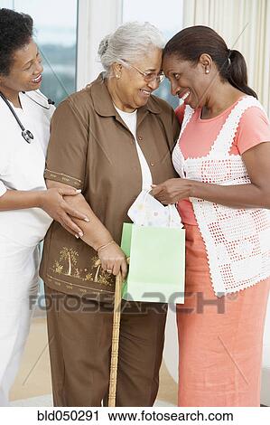 Stock Image - African American mother and adult daughter touching foreheads. Fotosearch