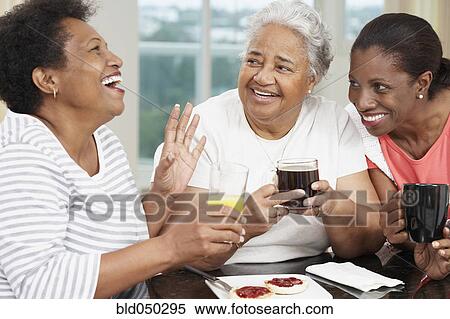 Stock Photography - African American mother and adult daughters at breakfast. Fotosearch