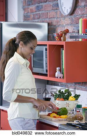Stock Image - African American woman chopping vegetables. Fotosearch