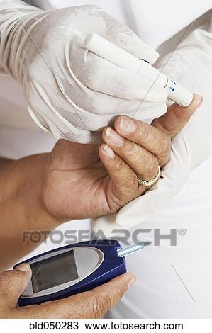 Stock Image - African American woman having blood sugar tested. Fotosearch