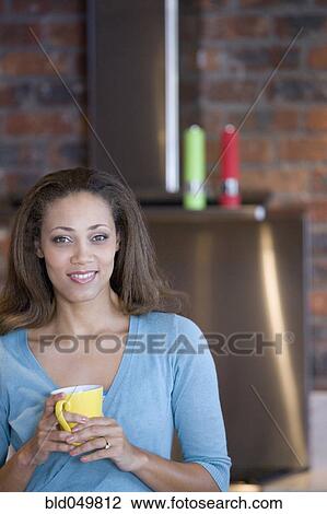Stock Image - African American woman holding coffee mug. Fotosearch