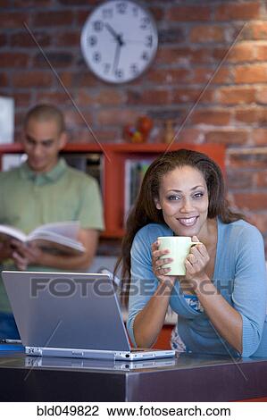 Stock Image - African American woman holding coffee mug. Fotosearch