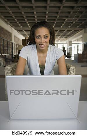 Stock Photo - African American woman sitting behind laptop. Fotosearch