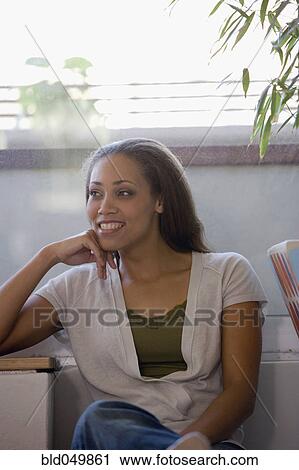 Stock Image - African American woman sitting indoors. Fotosearch