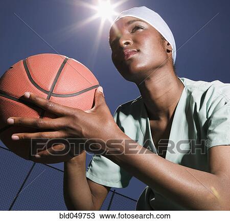 Stock Image - African woman holding basketball. Fotosearch
