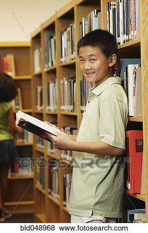 Stock Photo - Asian boy holding library book. Fotosearch