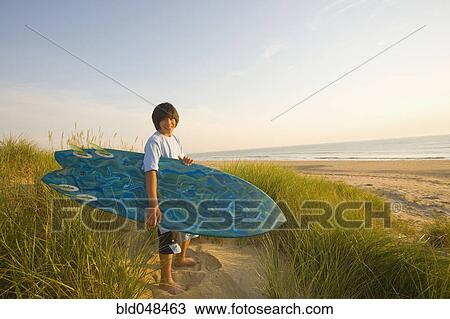 Asian boy holding surfboard at beach View Large Photo Image Stock Image - Asian boy holding surfboard at beach. Fotosearch