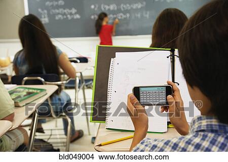 Picture - Asian boy using calculator in class. Fotosearch