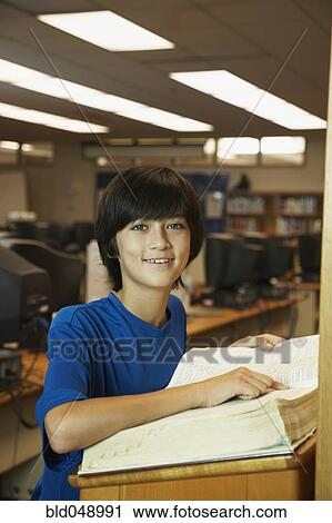 Stock Image - Asian boy using library dictionary. Fotosearch