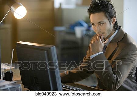 Stock Image - Asian businessman looking at computer. Fotosearch
