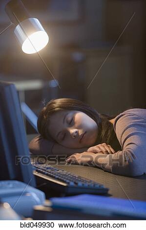 Stock Image - Asian businesswoman sleeping on desk. Fotosearch