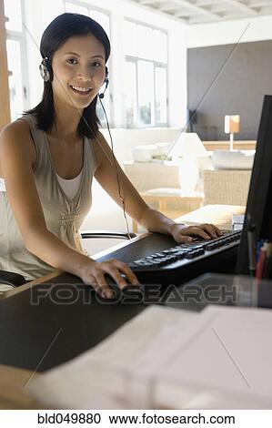 Stock Image - Asian businesswoman wearing headset. Fotosearch